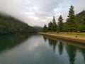 Beautiful early morning view of a creek with reflections of blue sky, foggy mountains and trees on water Royalty Free Stock Photo