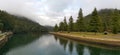 Beautiful early morning view of a creek with reflections of blue sky, foggy mountains and trees on water Royalty Free Stock Photo