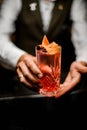 view of crystal glass with bright alcoholic cocktail in hands of male bartender