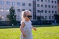 View on a cute little toddler girl in Sunglasses in the city park on a sunny summer day. Girl has happy fun with cheerful smiling Royalty Free Stock Photo