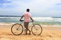 View of a cyclist standing on the sand enjoying the sea waves Royalty Free Stock Photo