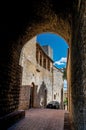 View of dark alleyway, brick building and tower in San Gimignano. Royalty Free Stock Photo