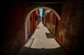 View from a dark arch with peeling walls to a narrow Italian street with multi-colored facades of houses Royalty Free Stock Photo