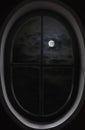 view of dark clouds, full moon through the oval window Royalty Free Stock Photo