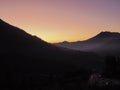 View of a dark mountain valley against a background of red-yellow sunset sky