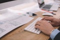 View of data analyst using computer keyboard near papers with graphs on table Royalty Free Stock Photo