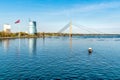 View of Daugava River with cable-stayed bridge, Latvian flag and boat that crosses the river, Riga. Royalty Free Stock Photo