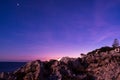 View at dawn of purple sky with stars and rocky pier in mallorca. dramatic and relaxing view of sunset in porto colom port with Royalty Free Stock Photo