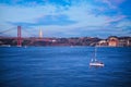 View of 25 de Abril Bridge over Tagus river, Christ the King statue and yacht boat in evening twilight. Lisbon, Portugal