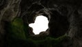 View from deep cave with grass, hole in rocky mountain, sunset. 3d render