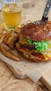 View of delicious burger and fries with glass of beer on wooden table Royalty Free Stock Photo