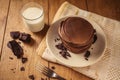 A view of delicious cocoa pancakes with dark chocolate and powdered sugar on a wooden table