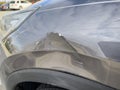 Close up view of a dent on the left side of a gray vehicle