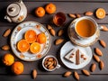 A view of a dining table with some oranges and sweet Indian dish Kaju Katli and a hot tea with teapot. Copy space