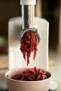 View directly on the working household meat grinder. The minced meat is placed in a ceramic bowl. Selective focus