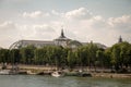A view from a distance of the Grand Palace and the embankment of the Seine on the opposite bank against the blue cloudy sky