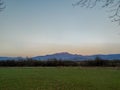 View of a distant mountain and green field on the ground on a beautiful sunny day evening or morning in nature wallpaper Royalty Free Stock Photo