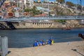 View at the Douro river, iconic D. Luis bridge and tourist people seat on banks