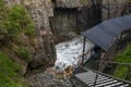 View down access stairs and water rushing through the entrance of remarkable cave