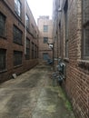View down a long alley between brick industrial buildings Royalty Free Stock Photo