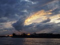 View of the dramatic sky above the sity at sunset with dark blue clouds and yellow flashes