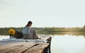 View of a Dreaming Girl sitting on a Pier on a Lake in the background. Royalty Free Stock Photo