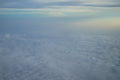 View of dreamy abstract white cloud with blue sky and sunrise light background from airplane window