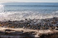 Pacific ocean waves on rocky shore and driftwood