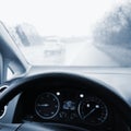 View from the driver - car interior with steering wheel and dashboard. Winter bad rainy weather and dangerous driving on the road Royalty Free Stock Photo
