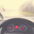 View from the driver - car interior with steering wheel and dashboard. Winter bad rainy weather and dangerous driving on the road Royalty Free Stock Photo