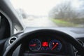 View from the driver - car interior with steering wheel and dashboard. Winter bad rainy weather and dangerous driving on the road Royalty Free Stock Photo