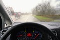 View from the driver - car interior with steering wheel and dashboard. Winter bad rainy weather and dangerous driving on the road Royalty Free Stock Photo