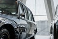 View of driver`s side black retro business class limousine with chrome mirror parked near another vintage car in a light Royalty Free Stock Photo