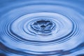 View of drops making circles on blue water surface isolated on background Royalty Free Stock Photo