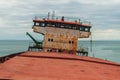 View of the dry cargo ship cabin from the side. Abandoned shipwrecked vessel stands on the shore tilted to the left