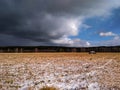 Beautiful landscape of the first snow falling on an autumn field with dry grass and sky with rain clouds Royalty Free Stock Photo