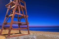 View of a dusk beach and starry sky with red wooden rescue tower Royalty Free Stock Photo