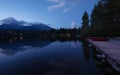 Dusk on a calm plateau of a mountain lake, water - borne peaks and moorings on the shore Royalty Free Stock Photo
