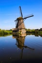 View on dutch water canal with reflection of one old windmill against deep blue cloudless summer sky in rural countryside - Royalty Free Stock Photo