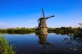 View on dutch water canal with reflection of one old windmill against deep blue cloudless summer sky in rural countryside - Royalty Free Stock Photo
