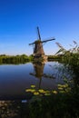 View on dutch water canal with reflection of one old windmill against deep blue cloudless summer sky in rural countryside - Royalty Free Stock Photo