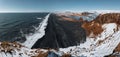 View from Dyrholaey lighthouse in Iceland looking out over the black sand beach below during winter with snow and