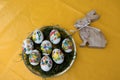 View on easter eggs and a wooden easter bunny on a yellow tablecloth with copy space