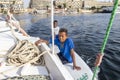 Aswan, Egypt - September 13, 2018: Egyptian children in a surf table hold on to the side of tourist boat in Nile river waiting for