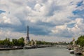 View of the Eiffel Tower along the Seine River. Bridge of Alexander the Third in Paris. Bright and cloudy sky