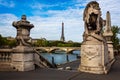 View of the Eiffel Tower framed by statues of the Alexander III Bridge spanning the Seine River in Paris Royalty Free Stock Photo