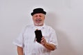 View of an elderly man holding his phone in his hand and smiling by looking at it on white Royalty Free Stock Photo