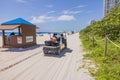 View of electric car near tourist service point of hotel on Miami Beach, under the blue sky with scattered clouds.