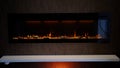 view on electric fireplace with artificial sparkling flame, decor for the interior, orange flame on crystals
