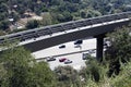 A view of an elevated tram rail and a highway passing cars in Los Angeles, California